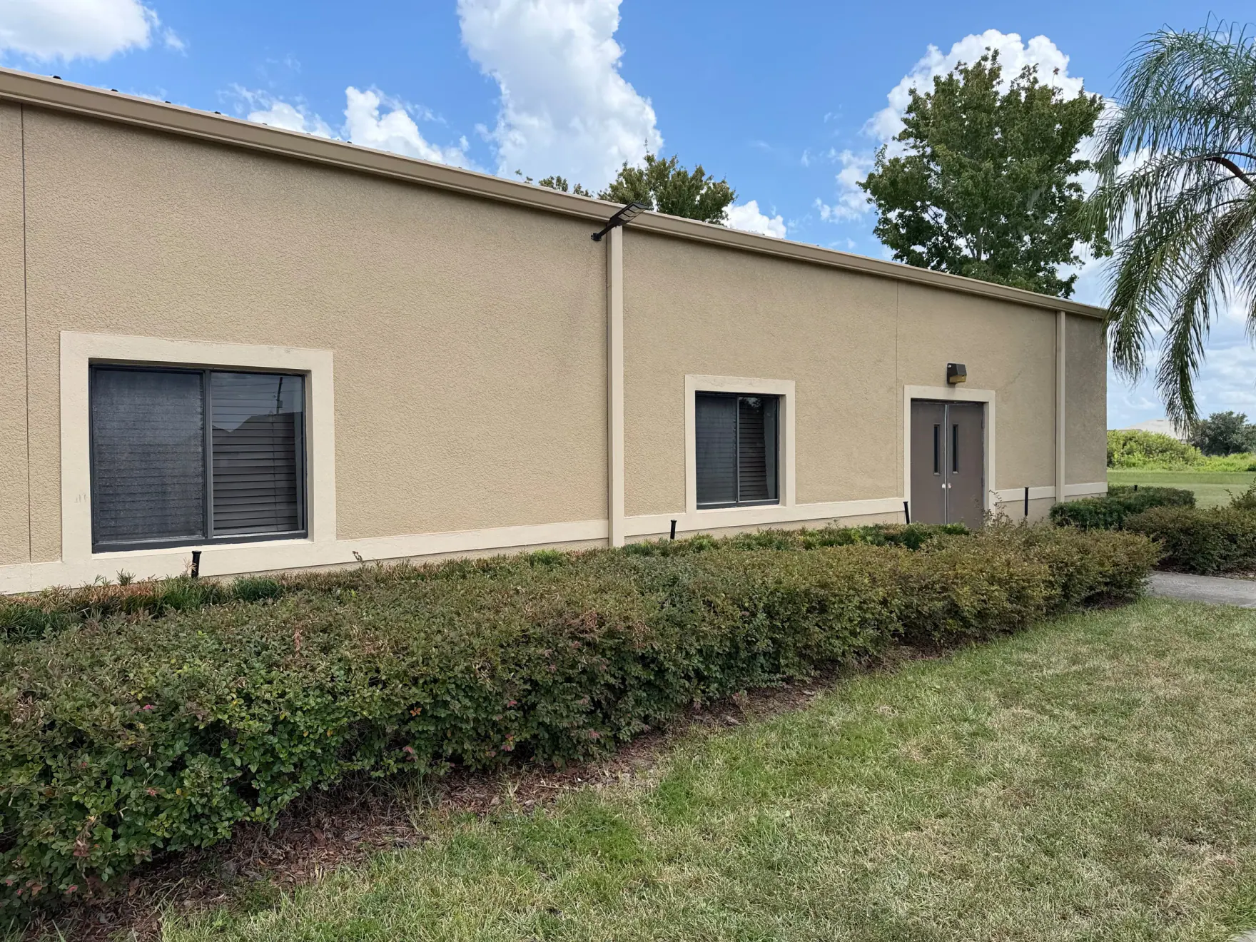Commercial building exterior with a downspout integrated along the tan wall and roof edge