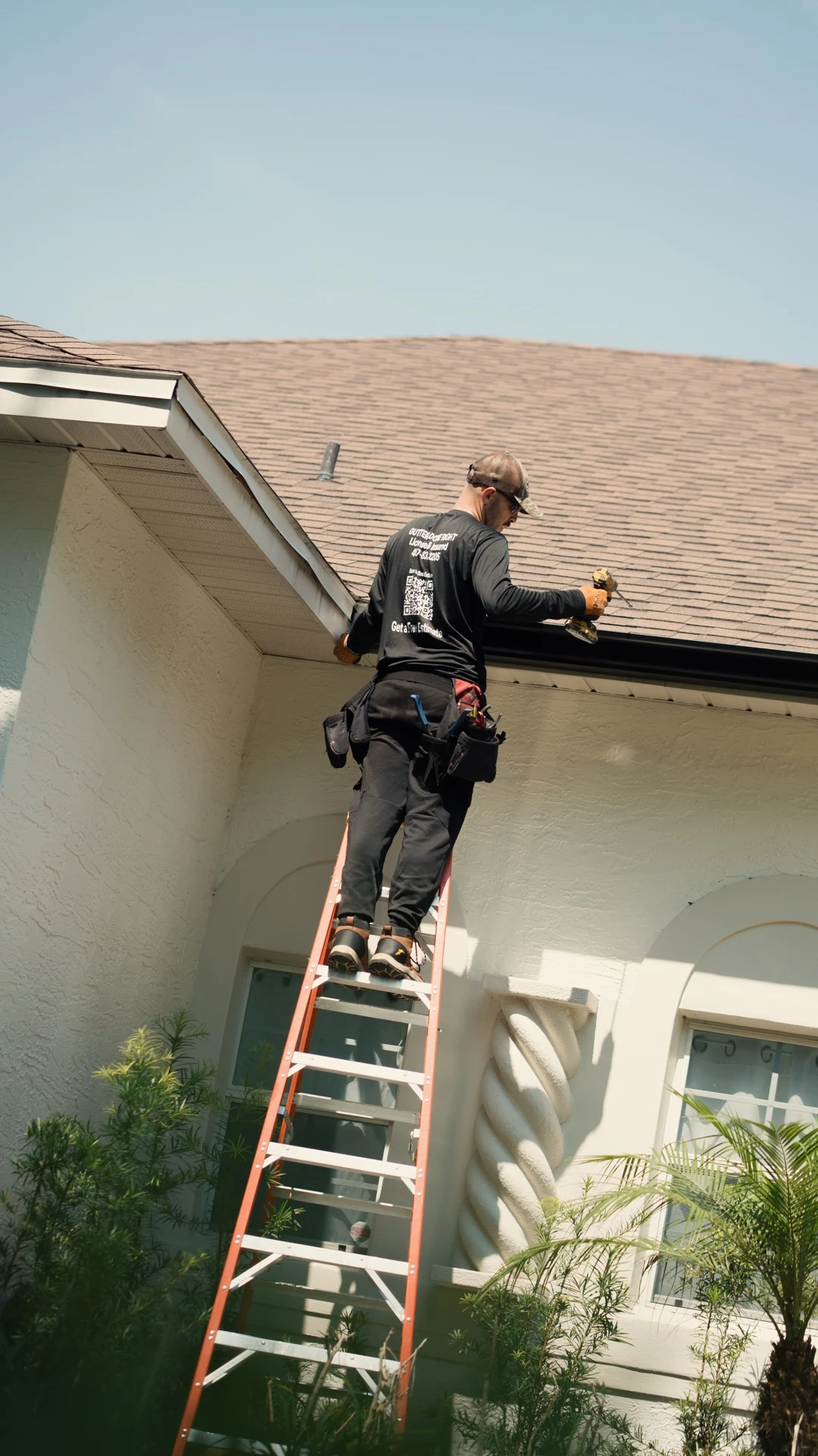 PrimeFlow field installer working from a ladder along a black residential gutter run