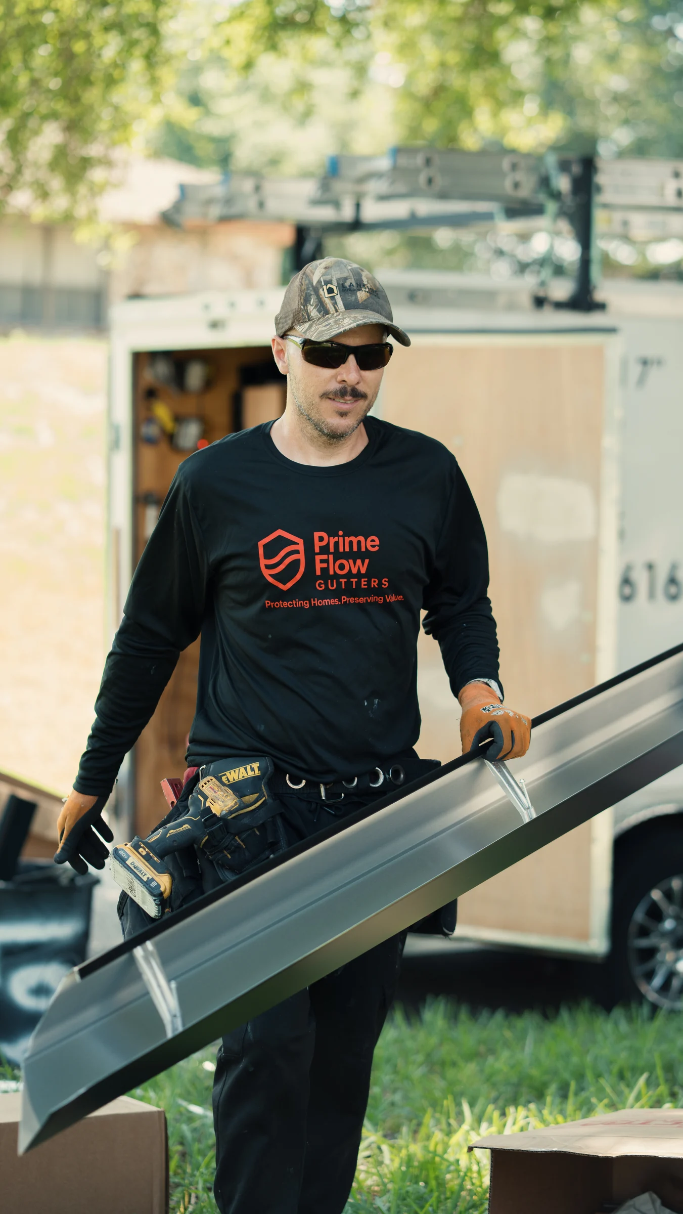 PrimeFlow field team member carrying a dark metal gutter section with internal hangers