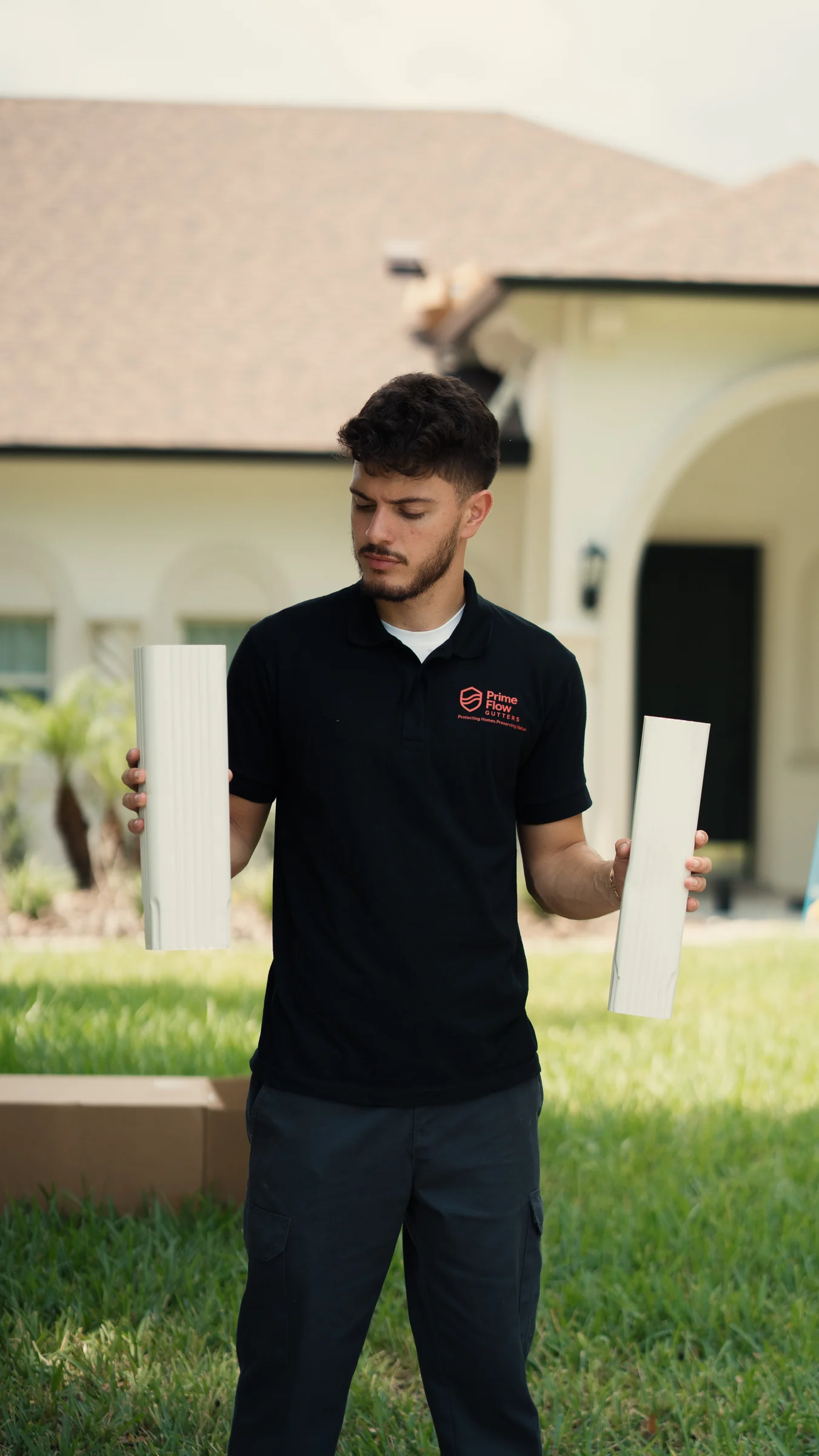 PrimeFlow field team member comparing two white gutter profile sections at a residential exterior