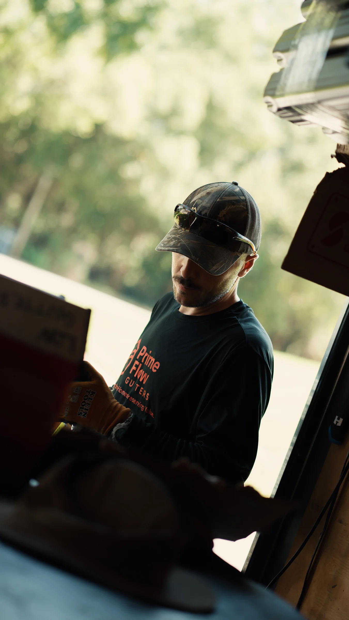 PrimeFlow field team member preparing gutter installation equipment near a residential roof edge