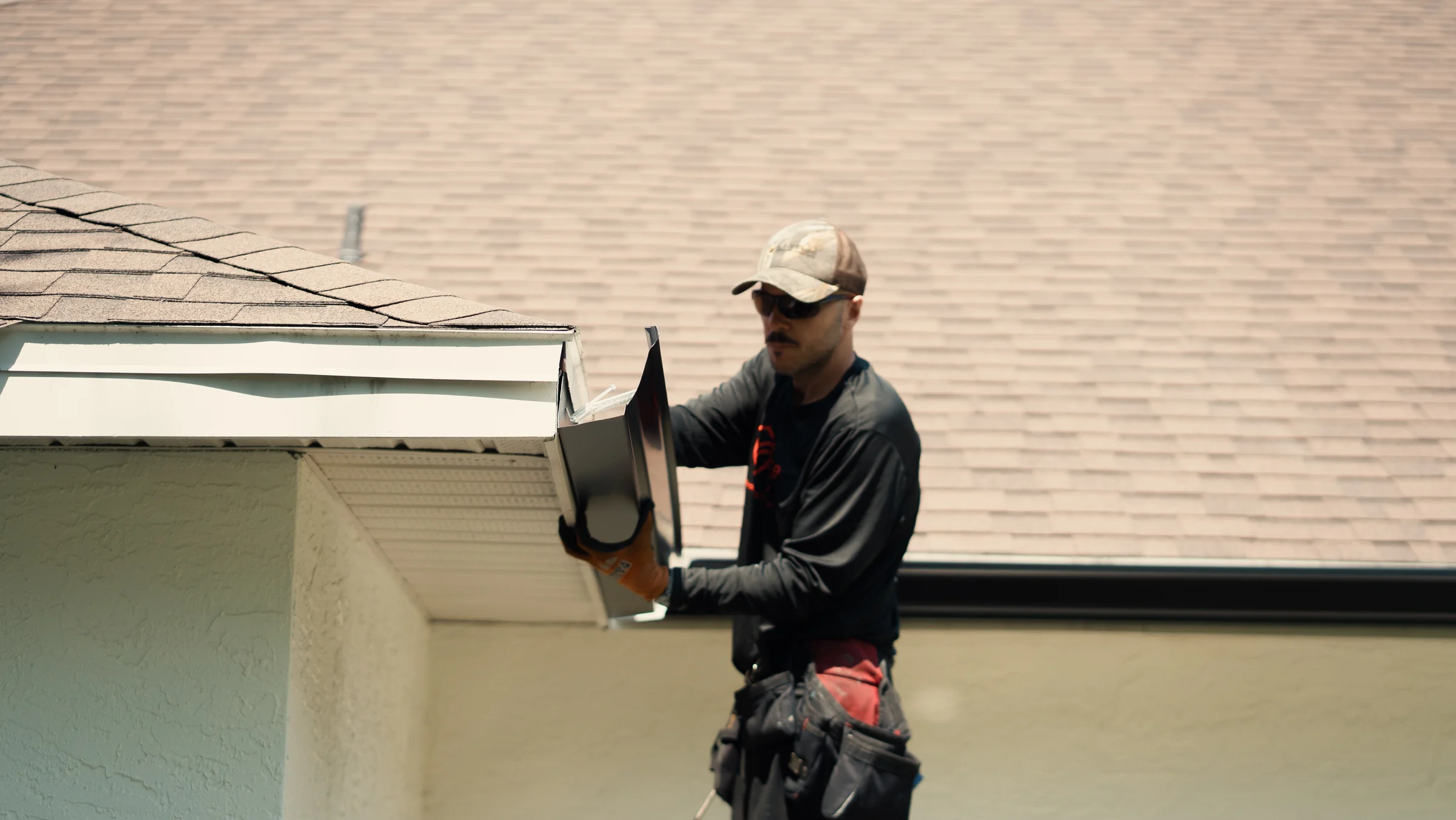 PrimeFlow field team member positioning a dark gutter section at a residential roof edge