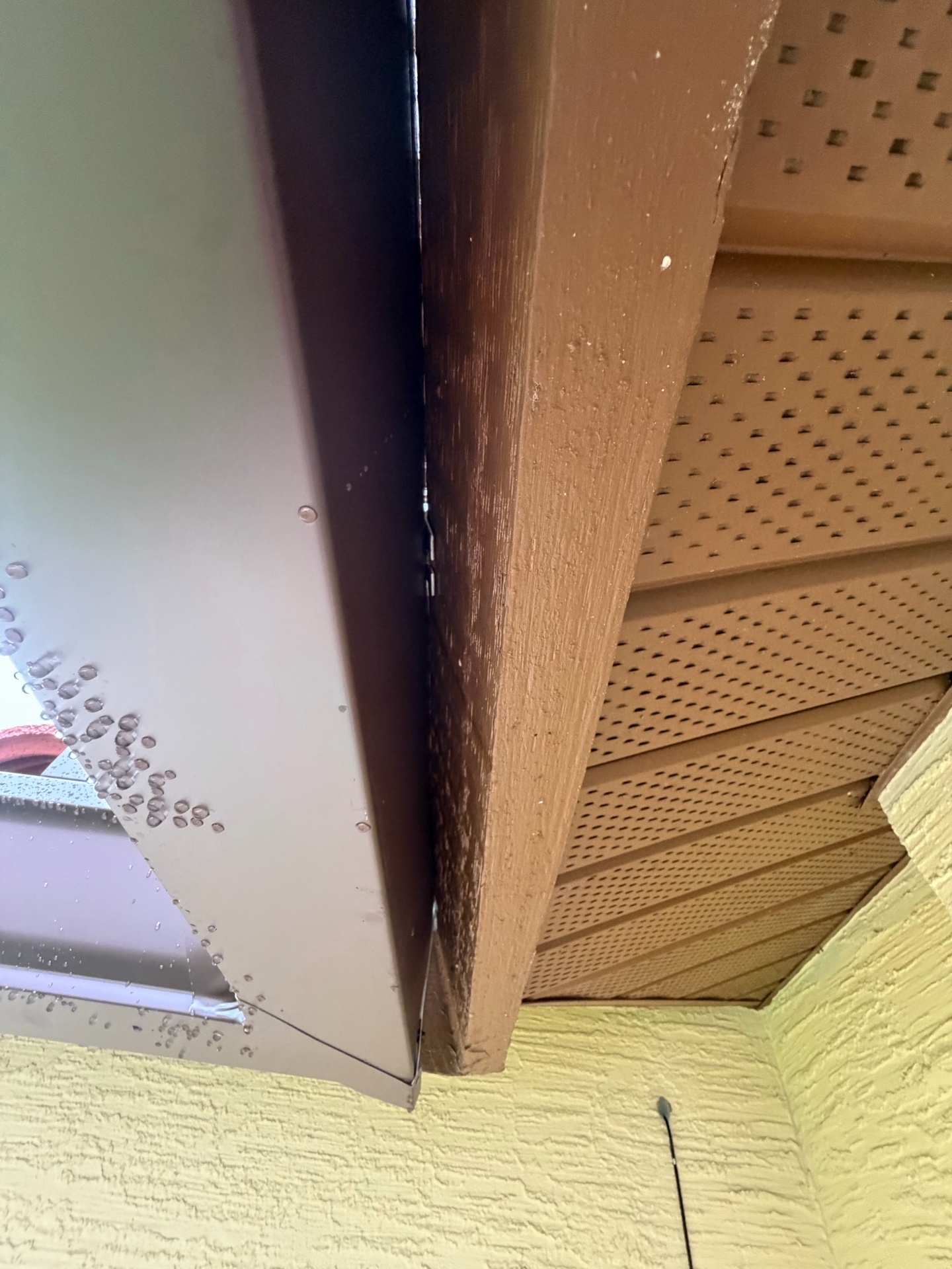 Existing gutter edge with a visible gap beside a wood fascia board and perforated soffit