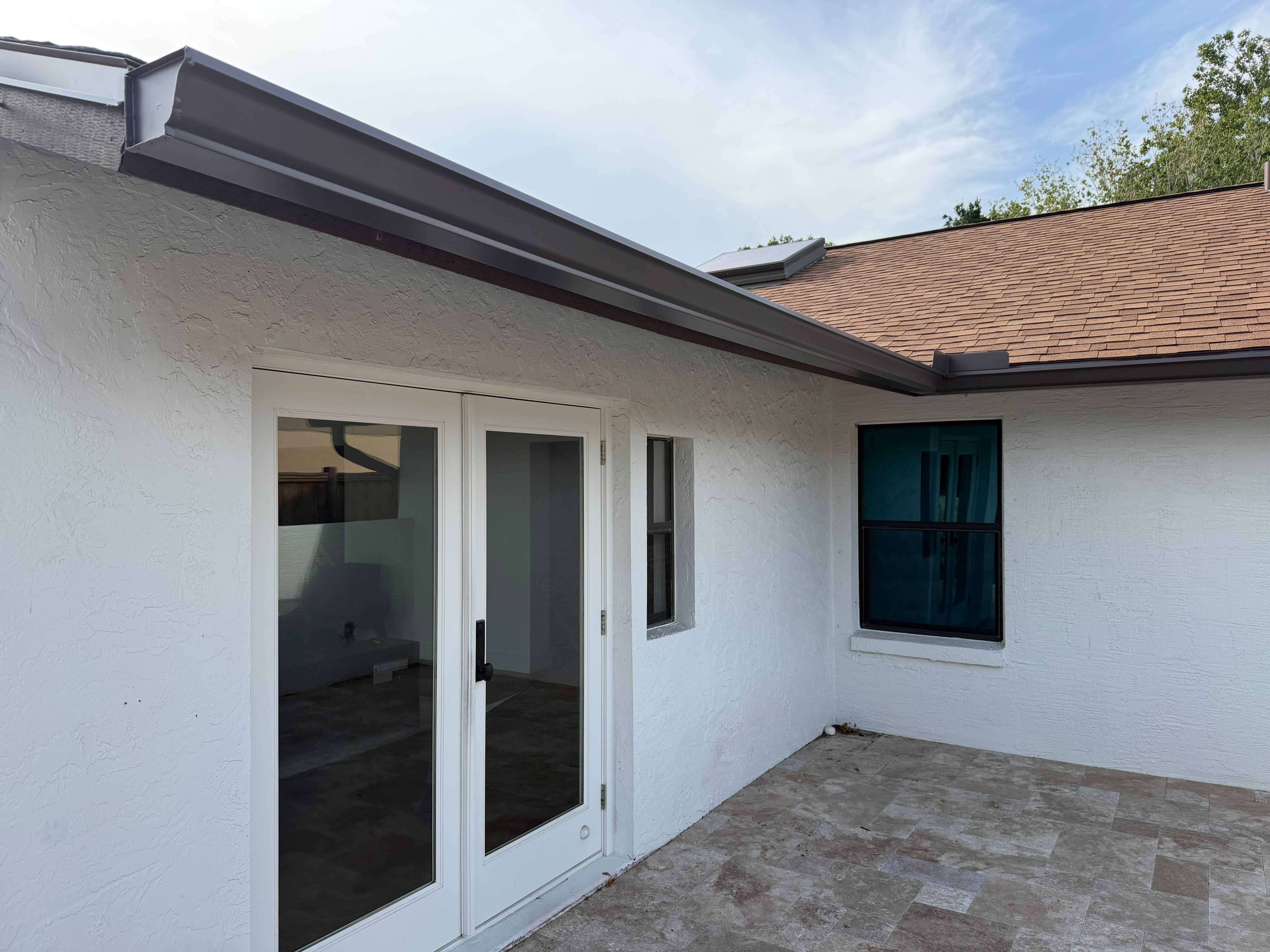 Dark seamless gutter installed beneath a Florida roof edge