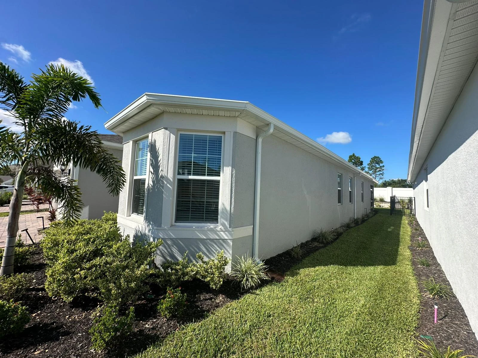 White gutter and downspout following the side elevation of a light-colored Florida home